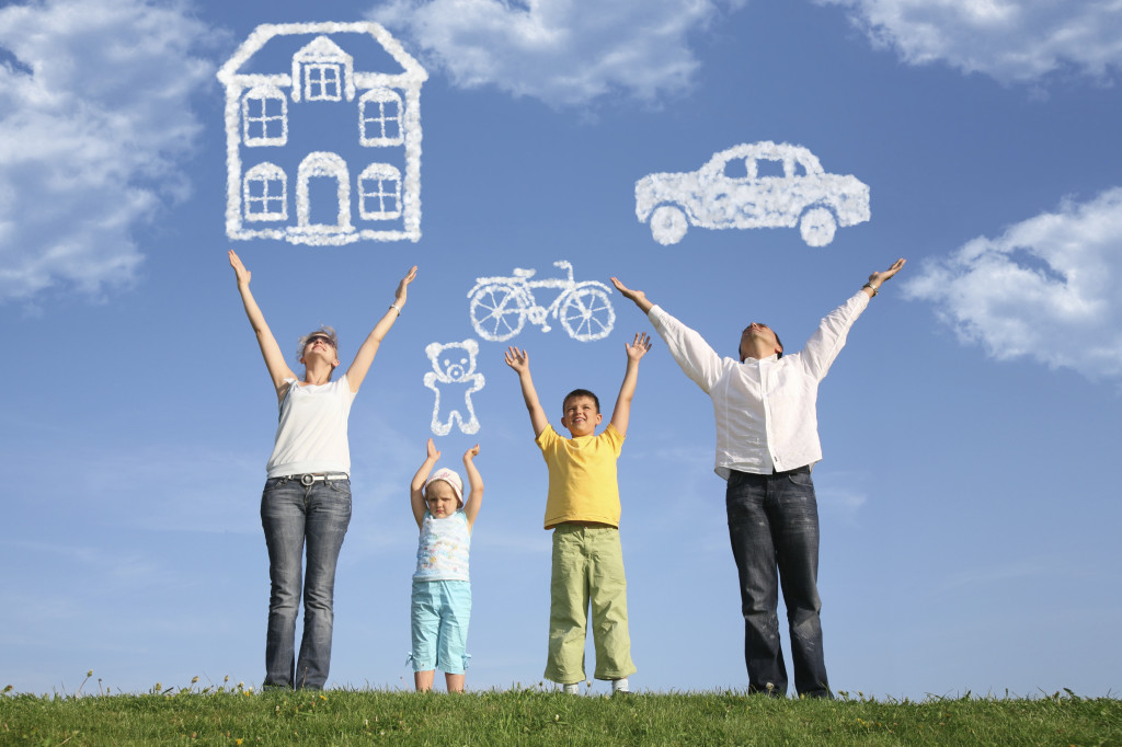 family of four on grass with hands up and dream